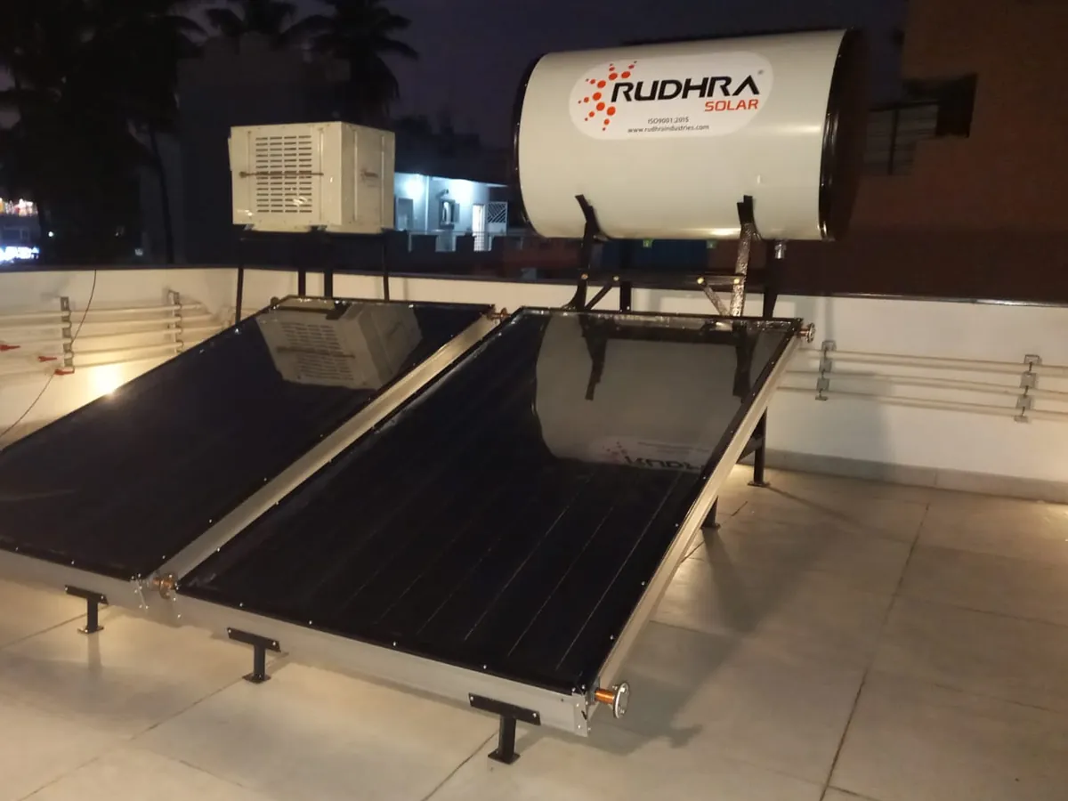 Domestic heat pump with a Rudhra Solar tank and two flat plate collectors on a terrace at dusk