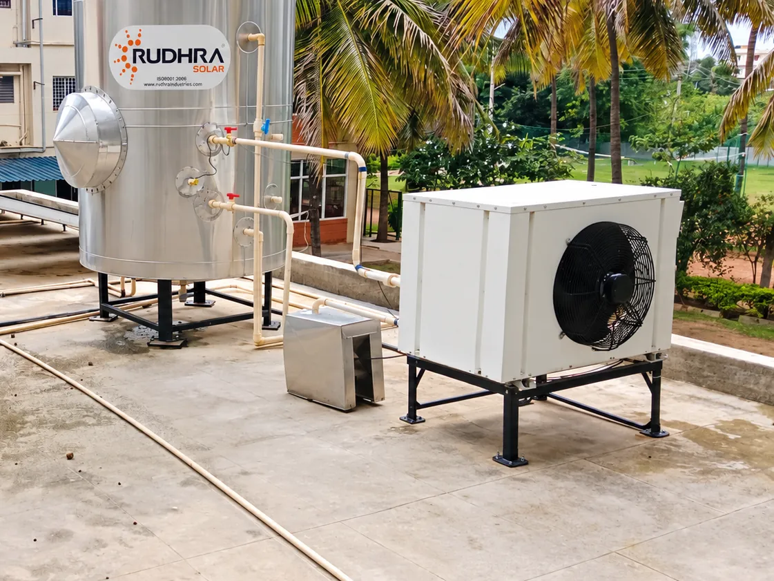 Rudhra heat pump working alongside a stainless steel solar storage tank on an institutional rooftop